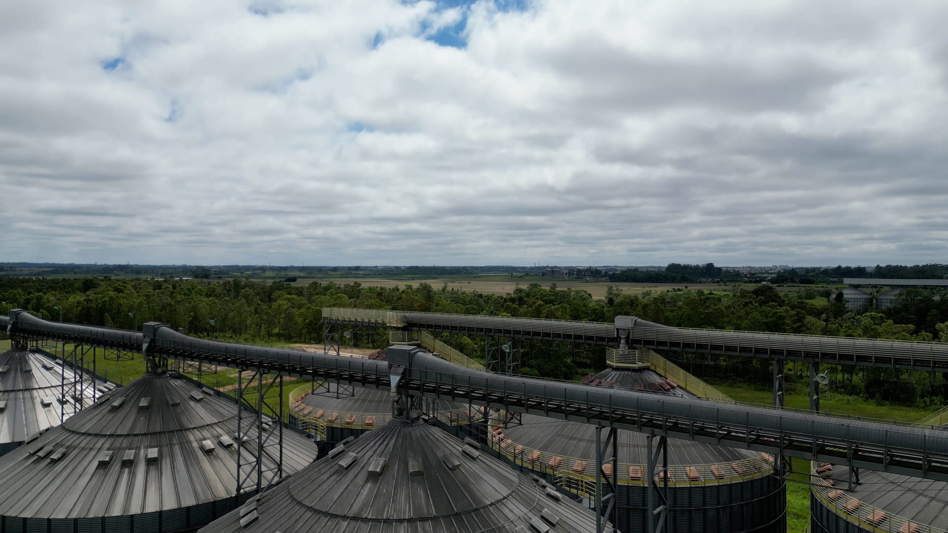 Vista aérea de silos de armazenagem de grãos com a lavoura ao fundo